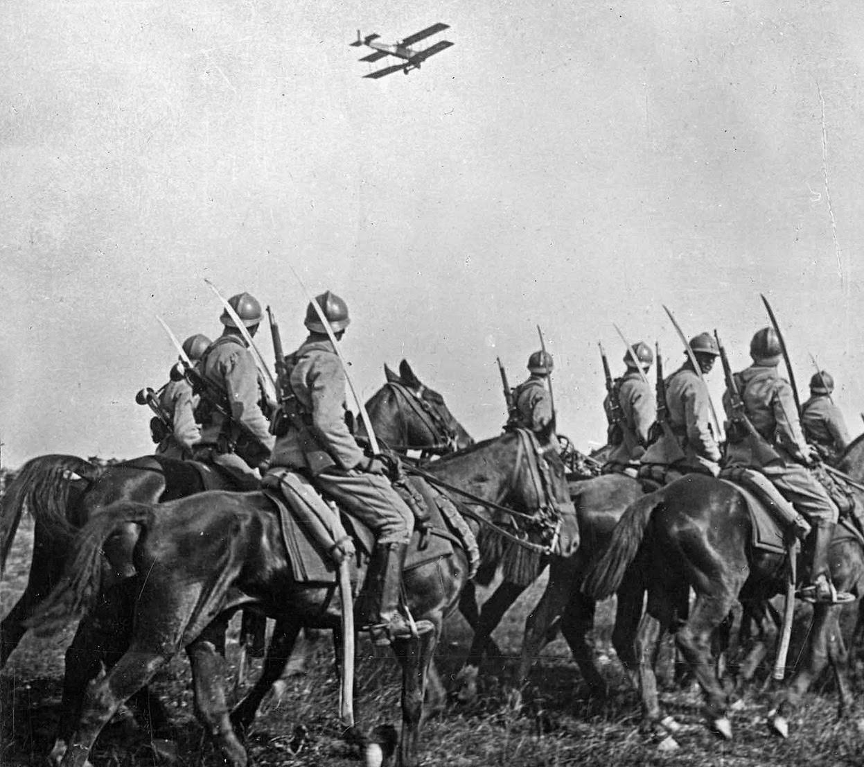 French Cavalry observe an Army airplane fly past.